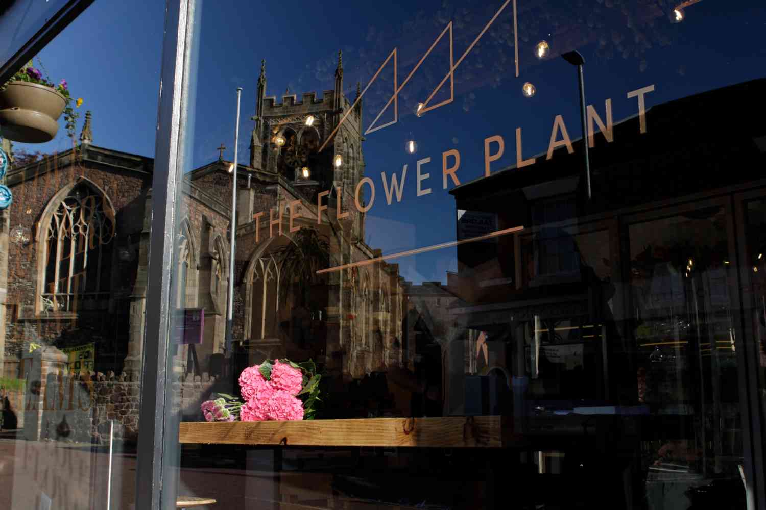 The Flower Plant florist window with reflection of St Mary's Church